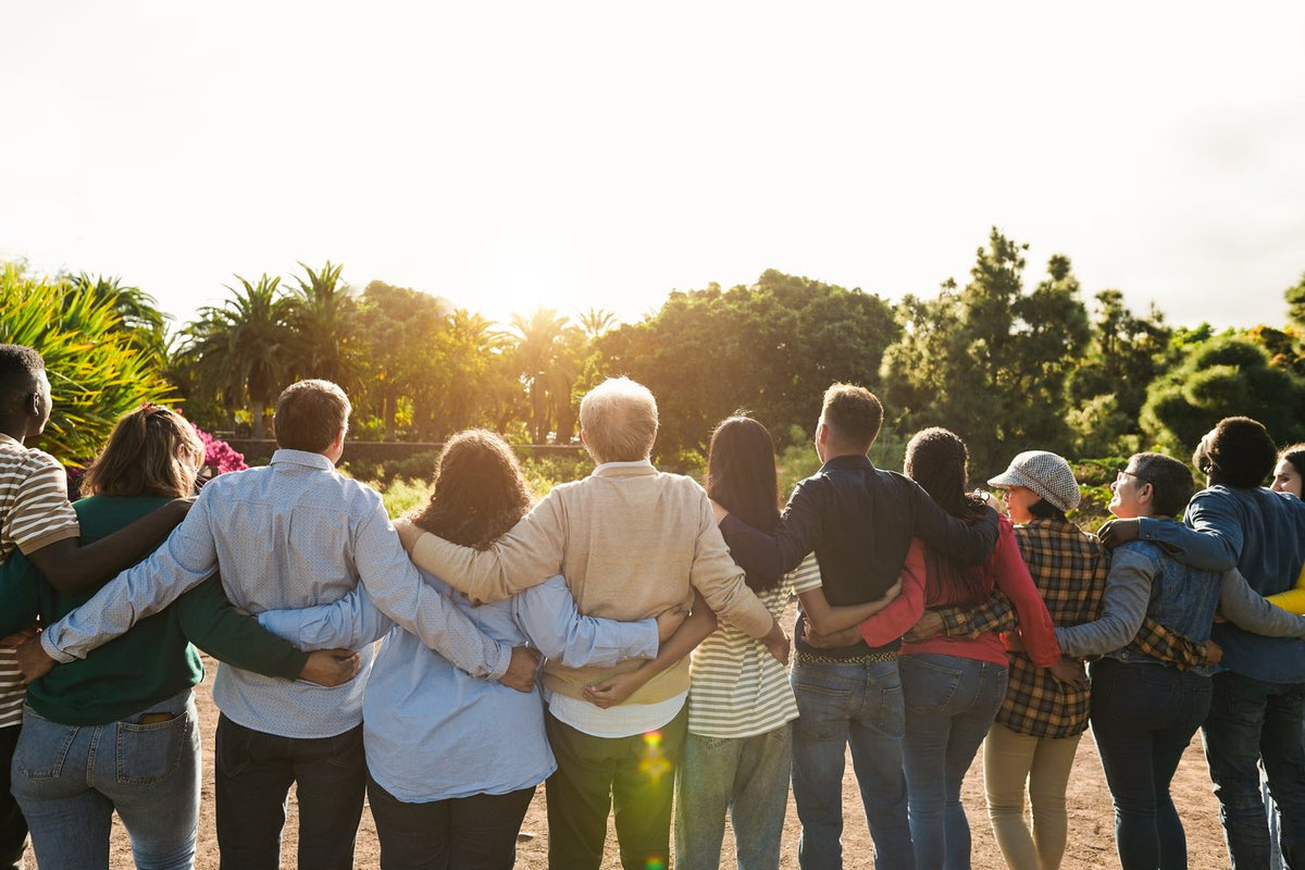A family standing together with their arms around each other at sunset